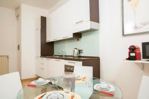 eine Küche mit einem Glastisch und weißen Schränken in der Unterkunft Beautiful apartment in Sta Maria delle Grazie by Easylife in Mailand