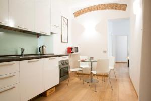 eine Küche mit weißen Schränken sowie einem Tisch und Stühlen in der Unterkunft Beautiful apartment in Sta Maria delle Grazie by Easylife in Mailand