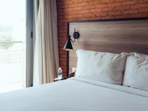 a bedroom with a white bed and a brick wall at ONOMO Airport Casablanca in Casablanca