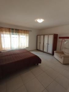 a bedroom with a bed and a couch and a chair at Maison G in LʼAquila +1 photo