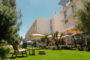 a garden with a table and chairs and umbrellas at ONOMO Airport Casablanca in Casablanca