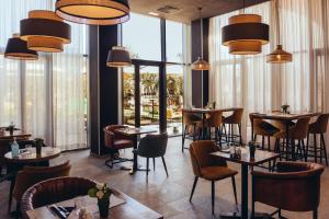 a restaurant with tables and chairs and large windows at ONOMO Airport Casablanca in Casablanca