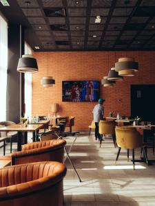 a restaurant with tables and chairs and a man standing in the background at ONOMO Airport Casablanca in Casablanca