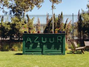 a green sign in the grass with potted plants on it at ONOMO Airport Casablanca in Casablanca