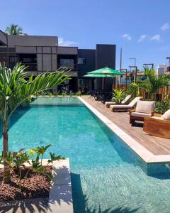 a large swimming pool with chairs and a building at Mani Milagres Studio - Gamboa Patacho in Pôrto de Pedras