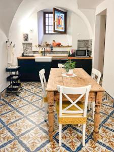 LA CURT guest house في Artogne: مطبخ مع طاولة خشبية وكراسي بيضاء