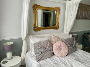 een slaapkamer met een wit bed met kussens en een spiegel bij Cosy Garden Flat, Private Roofed Hot Tub & Four Poster Bed in York