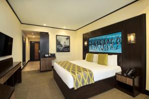 um quarto de hotel com uma cama e uma televisão de ecrã plano em Ramada Resort By Wyndham Dar es Salaam em Dar es Salaam