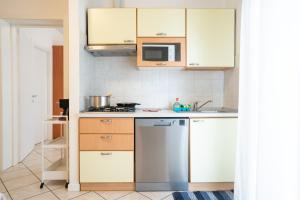 La cuisine est équipée de placards blancs et d'un réfrigérateur en acier inoxydable. dans l'établissement Residence Millennium, à Rimini