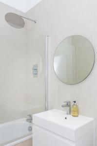 a white bathroom with a sink and a mirror at Sun drenched 1 bedroom apartment in Farringdon in London