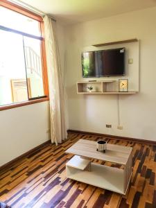 a living room with a coffee table and a flat screen tv at Villa Salluzzi Apart Hotel in Tacna