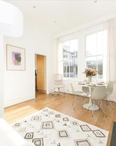 a white living room with a table and chairs at Sun drenched 1 bedroom apartment in Farringdon in London