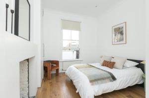 a white bedroom with a bed and a fireplace at Sun drenched 1 bedroom apartment in Farringdon in London