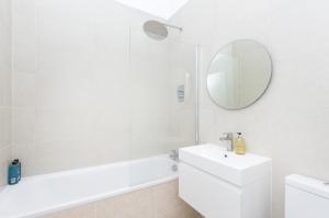 a white bathroom with a sink and a mirror at Sun drenched 1 bedroom apartment in Farringdon in London