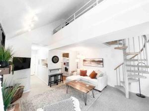 ein weißes Wohnzimmer mit einer weißen Couch und einer Treppe in der Unterkunft Top (third) floor loft condo. Full resort access. in Claysburg