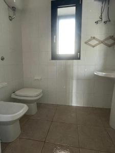 a bathroom with a toilet and a sink and a window at Caletta Relax by Blu Sardinia in La Caletta +20 photos