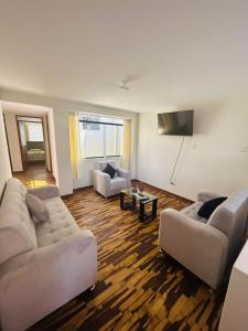 ein Wohnzimmer mit 2 Sofas und einem Flachbild-TV in der Unterkunft Villa Salluzzi Apart Hotel in Tacna