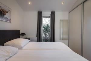 een slaapkamer met 2 witte bedden en een raam bij Vakantiepark Latour in Oirschot