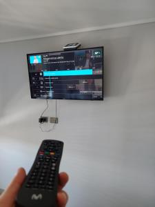 a person holding a remote control in front of a television at Departamento Ejecutivo Concepción in Concepción