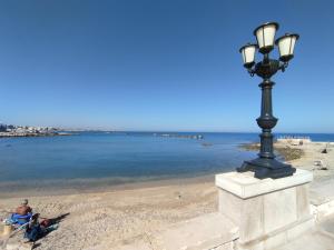 a lamp post on the beach with people sitting on the beach at Casa Mistral in Bari +6 photos