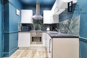 uma cozinha com armários brancos e paredes azuis em Urban Lux - Modern One-Bedroom Flat in Southend-On-Sea - Southend Stays em Southend-on-Sea