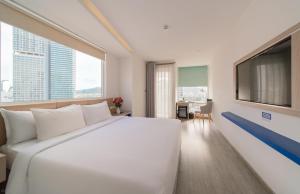 a large white bed in a room with a large window at Le's Cham Hotel in Nha Trang