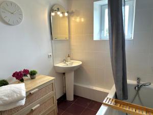 a bathroom with a sink and a clock on the wall at Sweet Omaha in Colleville-sur-Mer
