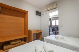 two beds in a small room with a window at Guest House Porto Clerigus in Porto