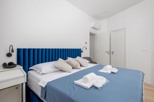 een slaapkamer met een blauw bed en handdoeken bij Penthouse Rio Kantrida in Rijeka