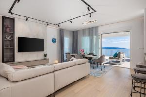een woonkamer met een witte bank en een televisie bij Penthouse Rio Kantrida in Rijeka