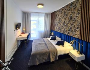 Nowogród的住宿－Hotel Kurpia Arte，配有一张床和一张书桌的酒店客房
