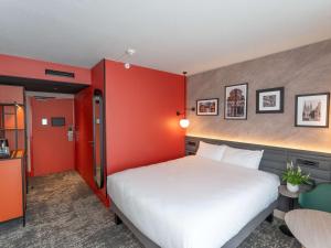 アンジェにあるホテル メルキュール アンジェ ラック ドゥ メーヌの白いベッドと赤い壁のベッドルーム1室