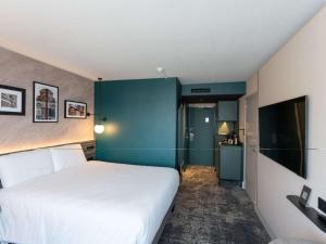1 dormitorio con cama blanca y pared azul en Hotel Mercure Angers Lac De Maine, en Angers