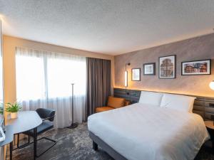 a hotel room with a bed and a desk at Hotel Mercure Angers Lac De Maine in Angers