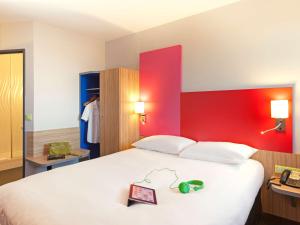 Schlafzimmer mit einem großen weißen Bett und einer roten Wand in der Unterkunft ibis Styles Romans-Valence Gare TGV in Alixan