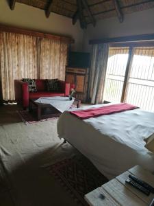 a bedroom with a large bed and a couch at Kwena Maribane Lodge in Erasmus