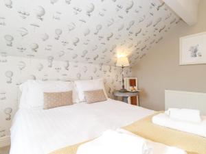 a bedroom with a white bed and a wall with hats at Church View in Grange Over Sands
