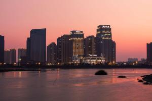 a city skyline at sunset with a river and buildings at Hilton Quanzhou Riverside in Quanzhou