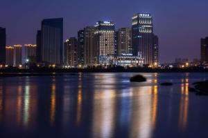 Eine Stadt leuchtet nachts mit einem großen Wasserkörper in der Unterkunft Hilton Quanzhou Riverside in Quanzhou