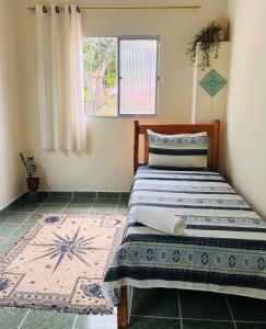 1 dormitorio con cama, ventana y alfombra en Hospedaria Além das Trilhas en Lençóis