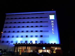 un hotel con un edificio iluminado en azul por la noche en ibis budget Manhuaçu, en Manhuaçu