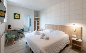 a bedroom with a large white bed and a desk at Malicorn' Appart-Hôtel in Malicorne-sur-Sarthe +16 photos