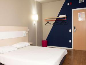 ein Schlafzimmer mit einem weißen Bett und einer blauen Wand in der Unterkunft ibis budget Manhuaçu in Manhuaçu