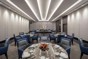 une salle de conférence avec des tables et des chaises bleues dans l'établissement Hilton Taizhou, à Taizhou