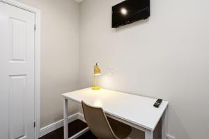 a white desk with a lamp and a chair at Smart Stay Studio Flat in London