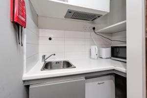 a small kitchen with a sink and a microwave at Smart Stay Studio Flat in London