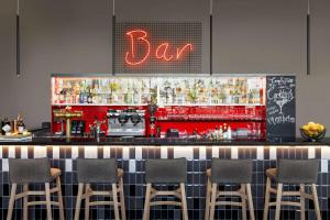 a bar with six chairs and a red bar at Vienna House Easy by Wyndham Pilsen in Pilsen