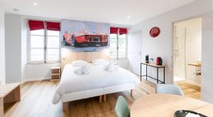 a bedroom with a white bed with a red car on the wall at Malicorn' Appart-Hôtel in Malicorne-sur-Sarthe
