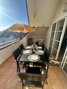 - une table avec des chaises et un parasol sur le balcon dans l'établissement Appartement 2 à 6 personnes dans un magnifique complexe de Vacances à Sainte-Luce, à Sainte-Luce