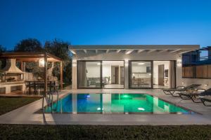 a swimming pool in the backyard of a house at Oresteia Exclusive Villa, a Sublime Retreat, By ThinkVilla in Tragaki